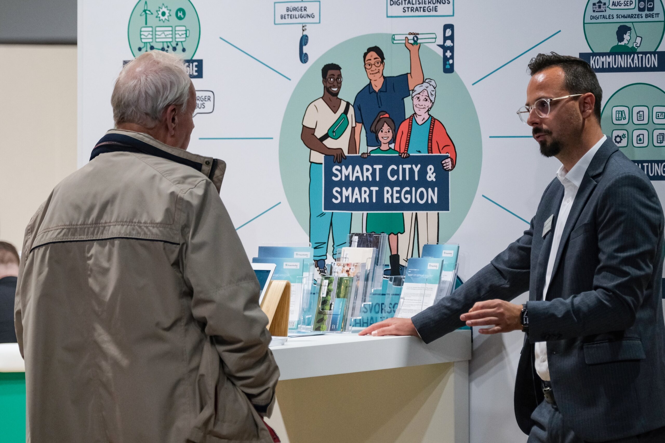 Besucher unterhält ishc mit unserem Kollegen und informiert sich am Stand über Themen wie Smart City und Smart Region